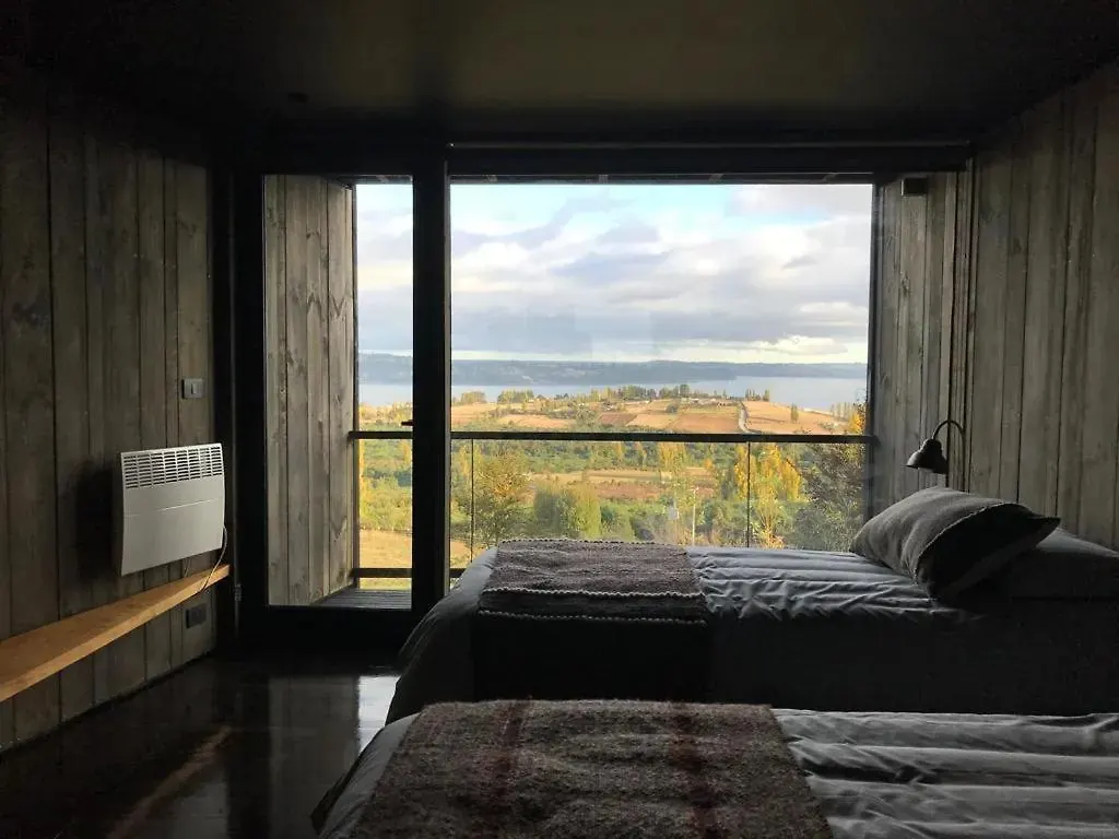 Habitación en penumbra que enmarca el paisaje verde y el mar